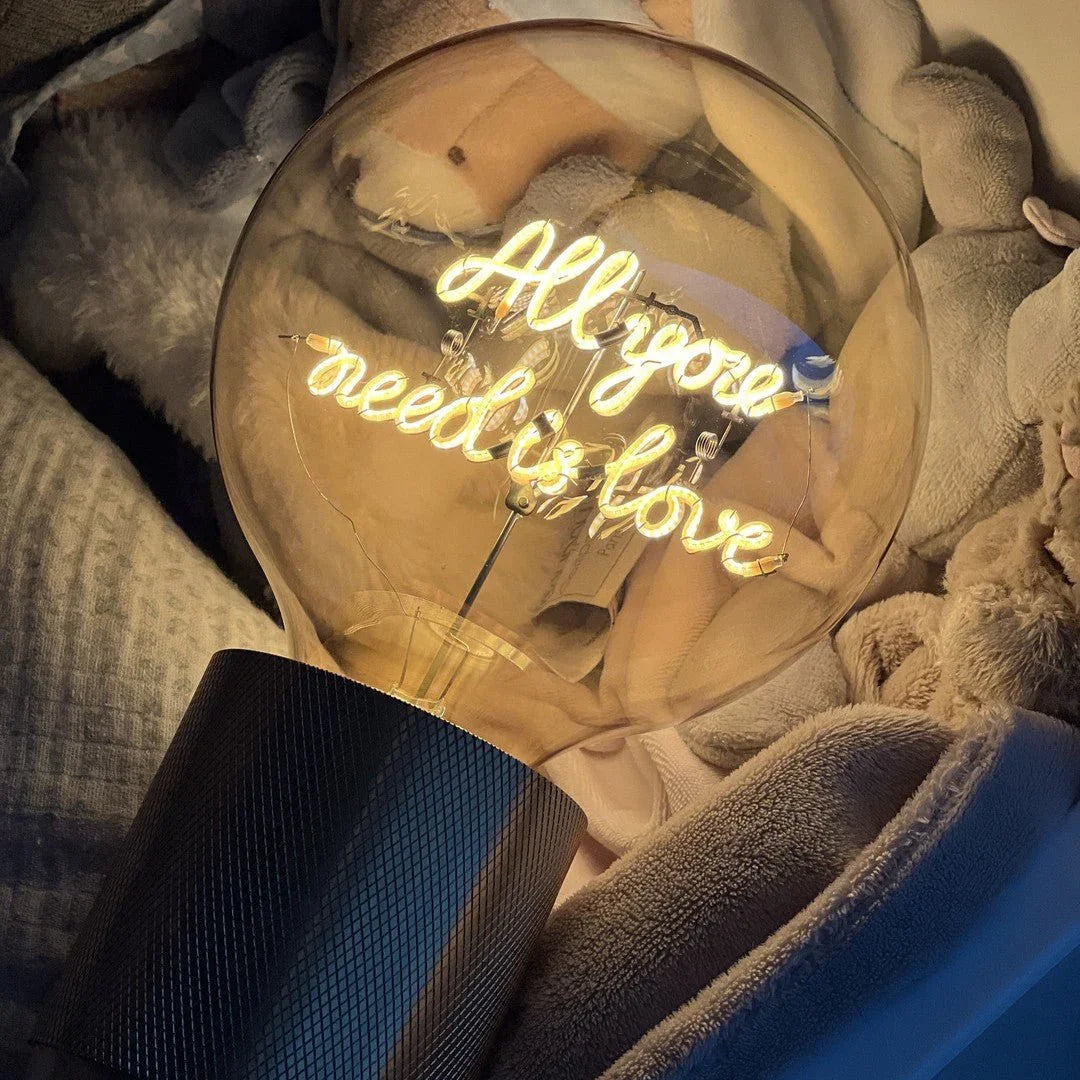 Ampoule LED design avec message lumineux All you need is love, sur socle sombre, ambiance cosy