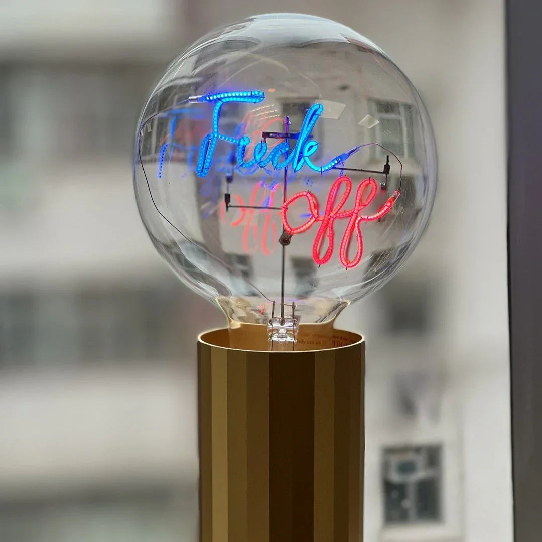 Ampoule LED design message lumineux bleu et rouge sur socle doré, intérieur moderne