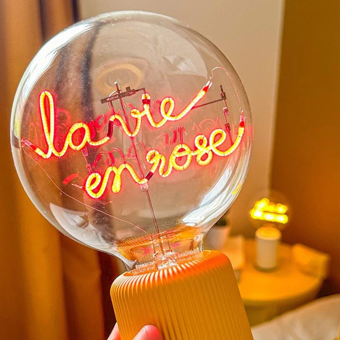 Ampoule LED design avec message lumineux « la vie en rose » sur socle jaune, ambiance cosy
