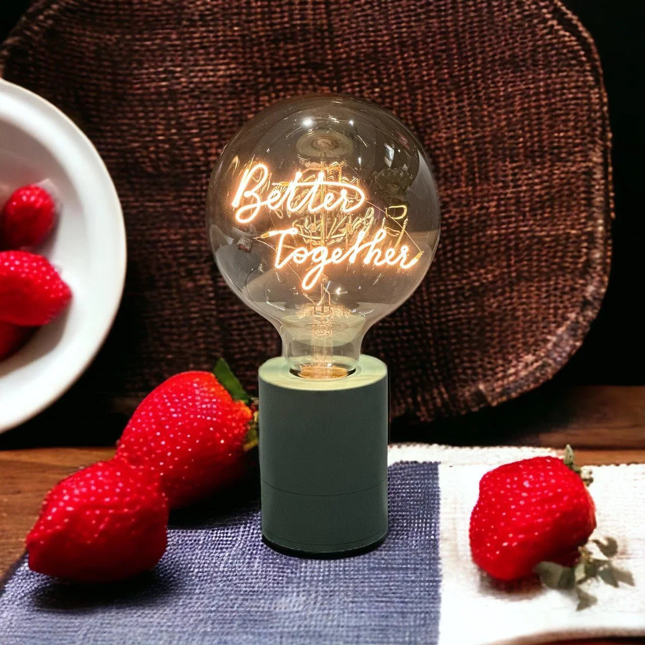 Ampoule LED message Better Together sur socle design, entourée de fraises, ambiance chaleureuse