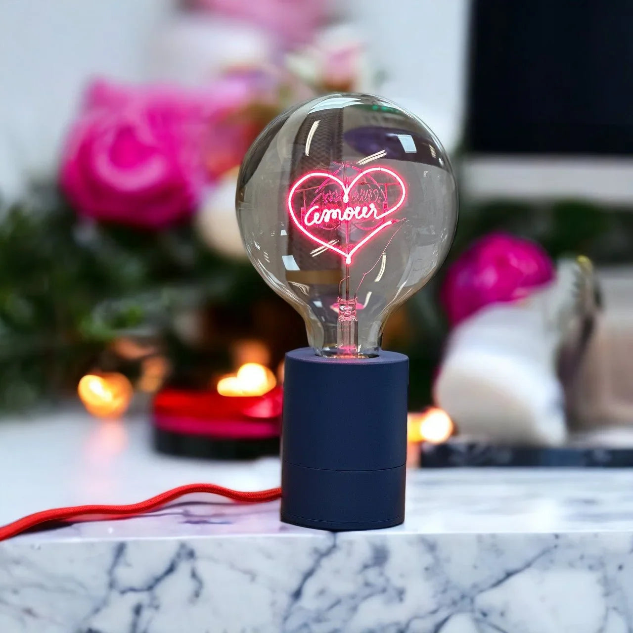 Ampoule LED décorative avec message lumineux 'amour' sur un socle bleu, fond romantique